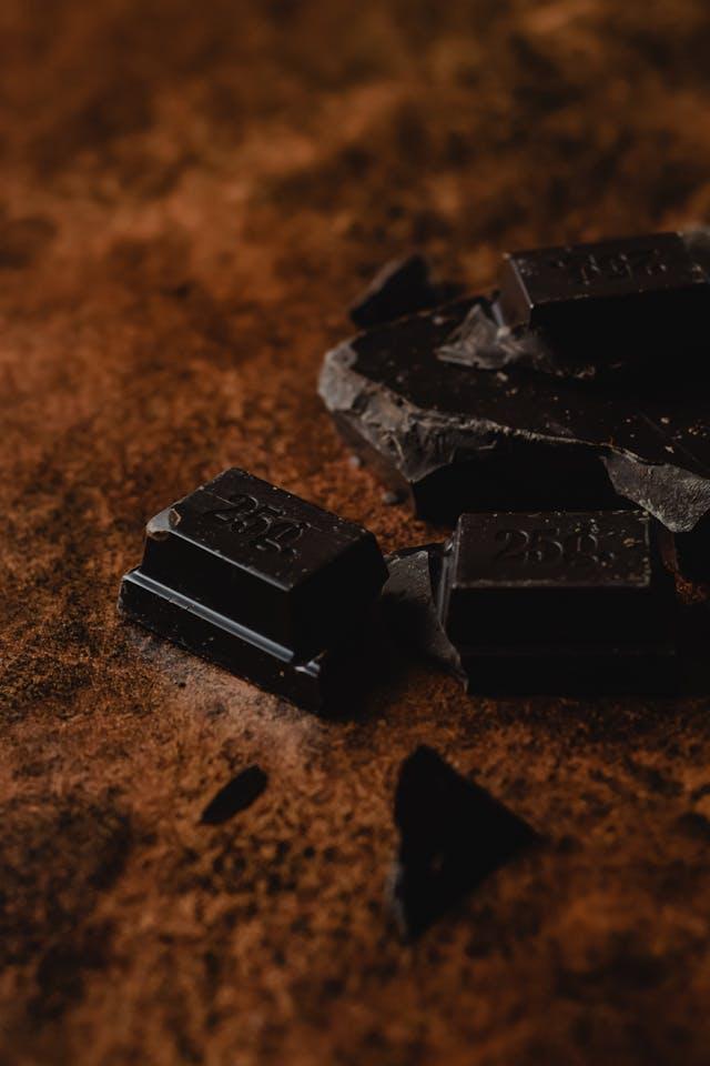 Carrés de chocolat noir posés sur du cacao