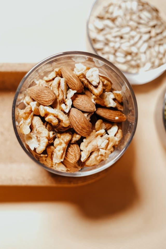 Vue de haut amandes et noix dans un verre sur une surface en bois clair