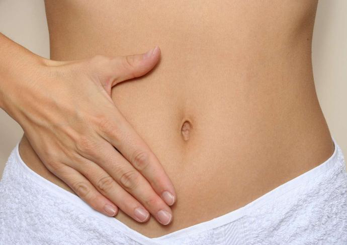 Ventre plat de femme avec une main posée dessus