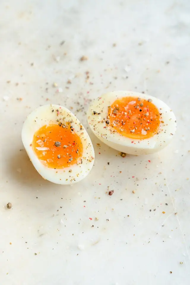 Deux moitiés d'œufs durs sur une table blanc-gris avec sel et poivre dessus